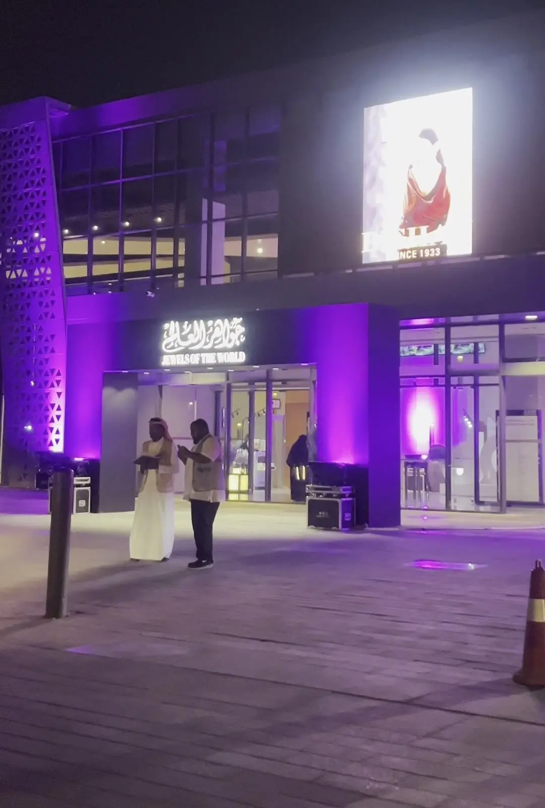 واجهة معرض المجوهرات ليلاً بإضاءة بنفسجية وضيوف عند المدخل